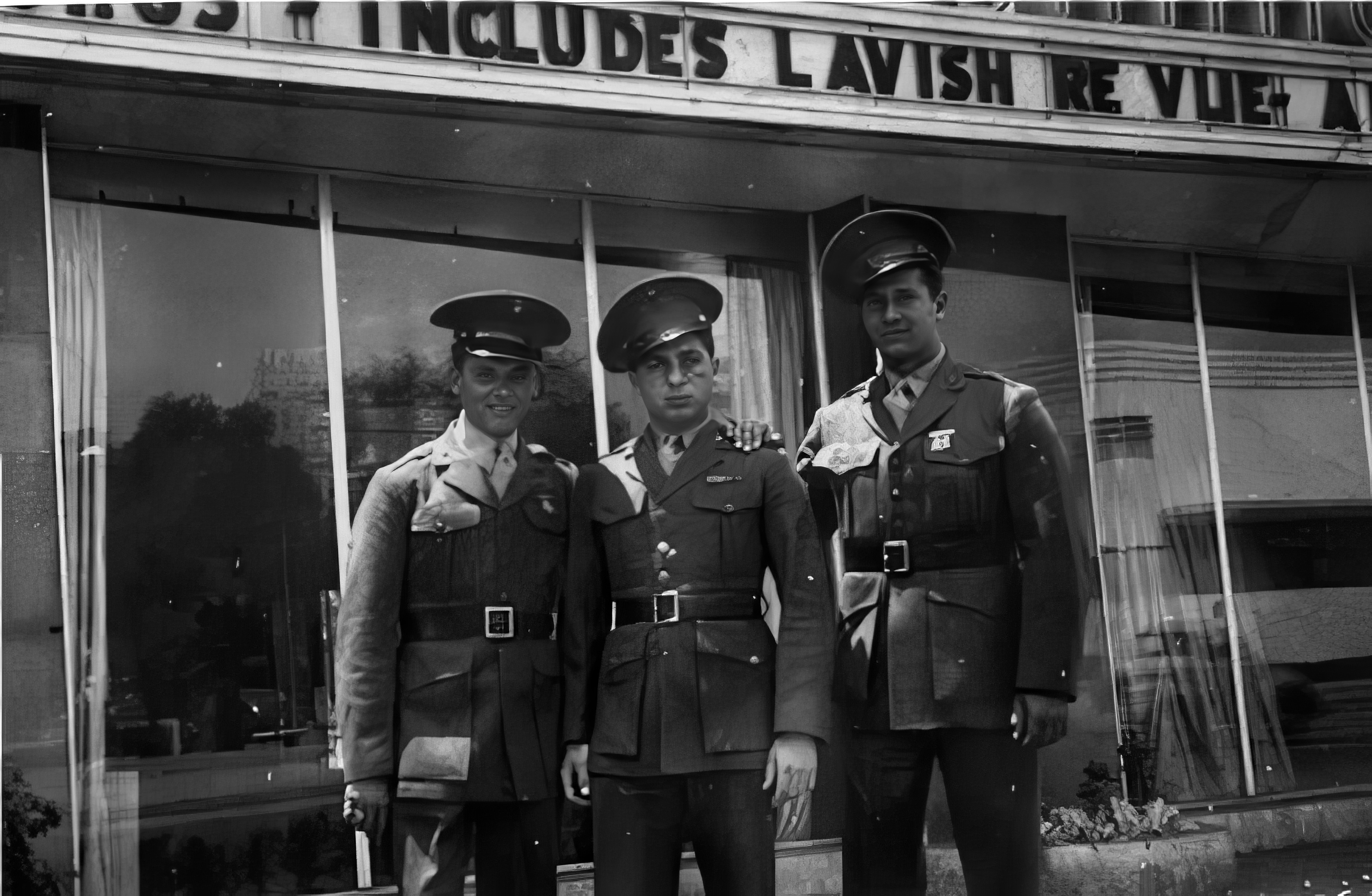 3 young men in uniform in front of a theater entrance