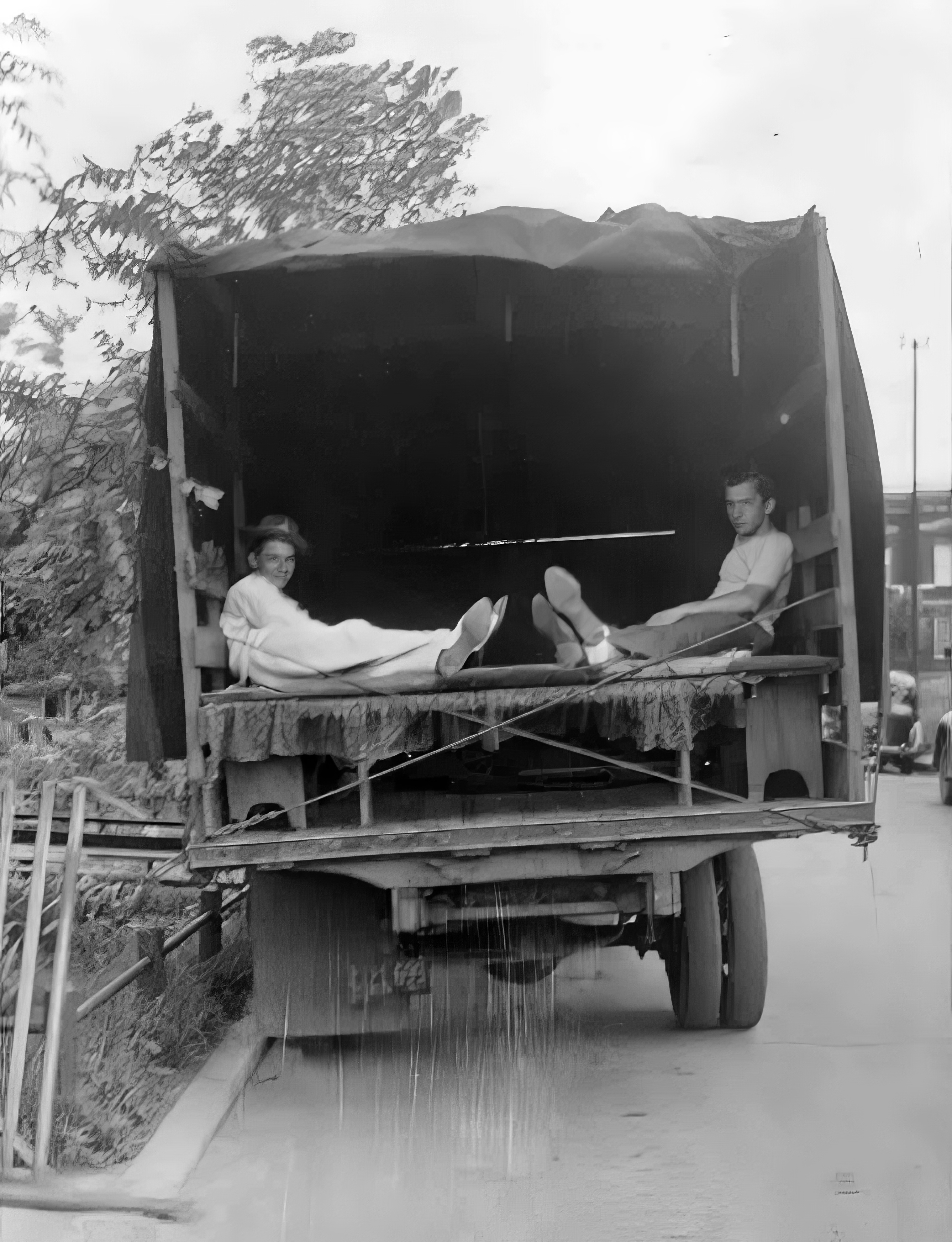 black and white photo of two men in the back of a truck