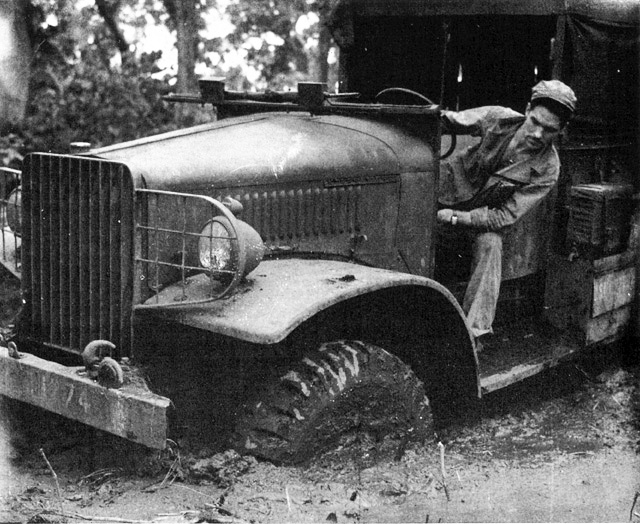 Marine in driver's seat of jeep looking at tire in mud